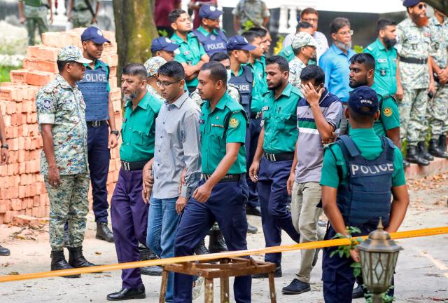 Police personnel escort detained army officers to the International Crimes Tribunal (ICT) court in Dhaka on October 22, 2025, over charges of crimes against humanity. A Bangladeshi court remanded in custody on October 22, 15 high-ranking army officers on charges of enforced disappearances and atrocities committed during the 2024 uprising that toppled the government. (Photo by AFP)