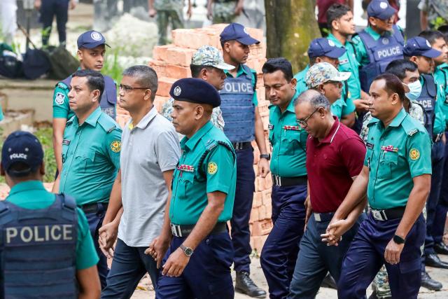 Police personnel escort detained army officers to the International Crimes Tribunal (ICT) court in Dhaka on October 22, 2025, over charges of crimes against humanity. A Bangladeshi court remanded in custody on October 22, 15 high-ranking army officers on charges of enforced disappearances and atrocities committed during the 2024 uprising that toppled the government. (Photo by AFP)