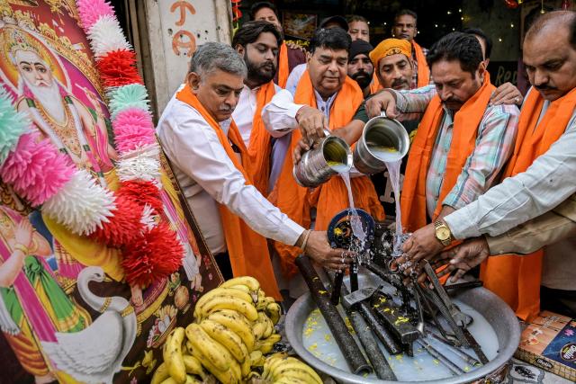 Devotees pour milk on hand tools as part of a religious ritual observed by craftsmen on the occasion of 'Vishwakarma Day' in Amritsar on October 22, 2025. (Photo by Narinder NANU / AFP)