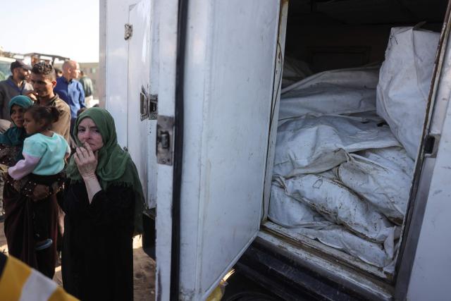 TOPSHOT - A Palestinian woman stands next to a refrigerated truck carrying the remains of unidentified Palestinians whose bodies were returned by Israel under a US-brokered ceasefire deal, outside Nasser Hospital in Khan Yunis, in the southern Gaza Strip, on October 22, 2025. (Photo by BASHAR TALEB / AFP)