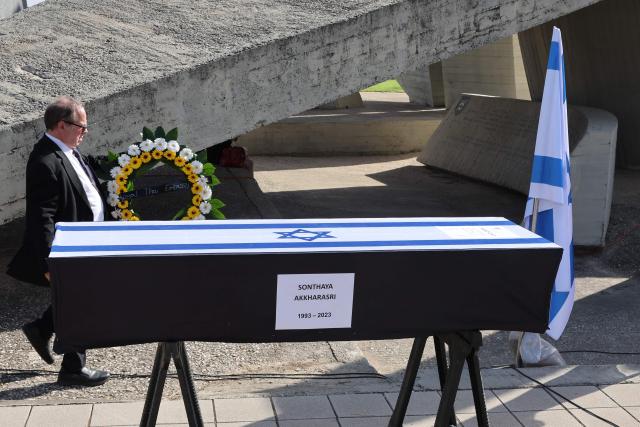 A man walks next to the coffin of Thai national Sonthaya Oakkharasri, who killed in the October 7, 2023, attack by Palestinian militants, ahead of a farewell ceremony at the Ben Gurion Airport in Tel Aviv on October 22, 2025, ahead of his flight back to Thailand. (Photo by Jack GUEZ / AFP)