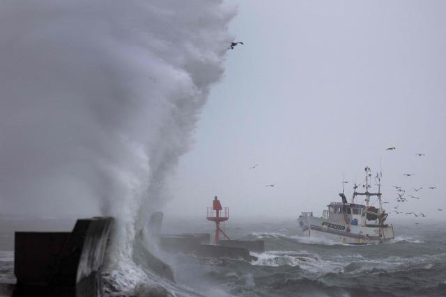 TOPSHOT - A fishing boat arrives at the port in Plobannalec-Lesconil, western France, October 22, 2025, as huge waves and strong winds hit the coast at the passage of the storm Benjamin. (Photo by Fred TANNEAU / AFP)