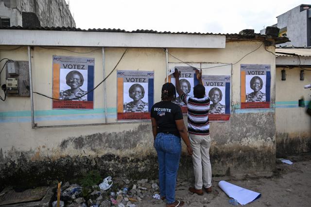 Supporters display on a wall a campaign poster of former Ivorian First Lady and presidential candidate for the Movement of the Capable Generations (MGC), Simone Ehivet Gbagbo, before her arrival for a campaign rally in Le Barron, in the working-class commune of Yopougon in Abidjan on October 22, 2025. The presidential election is scheduled for October 25, 2025. (Photo by SIA KAMBOU / AFP)