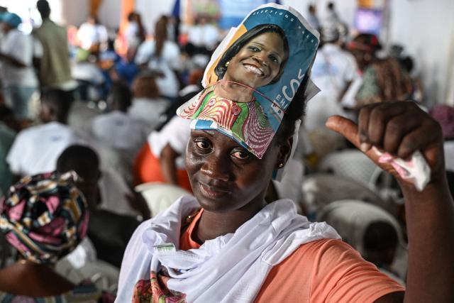 A supporter carries her poster on her head of former Ivorian First Lady and presidential candidate for the Movement of the Capable Generations (MGC), Simone Ehivet Gbagbo, before her arrival for a campaign rally at Le Barron, in the working-class commune of Yopougon, in Abidjan on October 22, 2025. The presidential election is scheduled for October 25, 2025. (Photo by Sia KAMBOU / AFP)