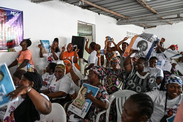 Supporters hold campaign posters of former Ivorian First Lady and presidential candidate for the Movement of the Capable Generations (MGC), Simone Ehivet Gbagbo, before her arrival for a campaign rally at Le Barron, in the working-class commune of Yopougon in Abidjan on October 22, 2025. The presidential election is scheduled for October 25, 2025. (Photo by Sia KAMBOU / AFP)