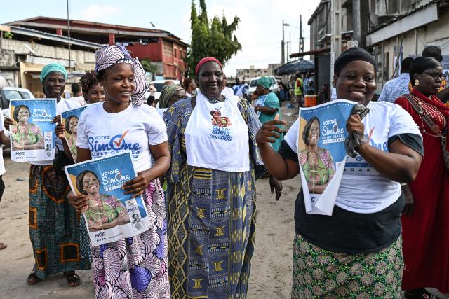 Supporters hold campaign posters of former Ivorian First Lady and presidential candidate for the Movement of the Capable Generations (MGC), Simone Ehivet Gbagbo, before her arrival for a campaign rally in Le Barron, in the working-class commune of Yopougon in Abidjan on October 22, 2025. The presidential election is scheduled for October 25, 2025. (Photo by Sia KAMBOU / AFP)