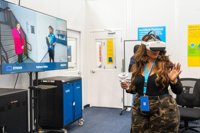 An Amazon employee uses a virtual reality headset to practice navigation, safety protocols, and package handling, during Amazon's "Delivering the Future" presentation at DUR3 Delivery Station in Milpitas, California on October 22, 2025. (Photo by Laure Andrillon / AFP)