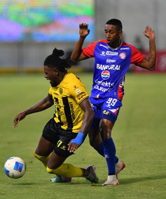 Real Espana's defender #21 Danilo Palacios and Xelaju's Brazilian forward #99 Romario fight for the ball during the first leg of the CONCACAF Central American Cup semifinal football match between Honduras's Real Espana and Guatemala's Xelaju at Francisco Morazan Stadium in San Pedro Sula, Honduras, on October 22, 2025. (Photo by Orlando SIERRA / AFP)