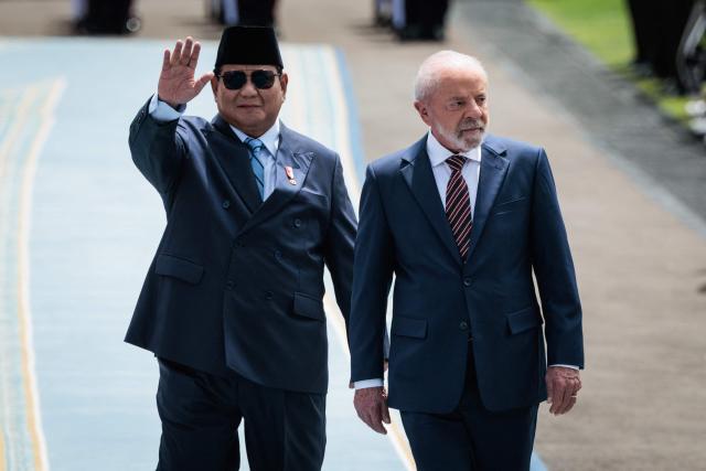 Brazil's President Luiz Inacio Lula da Silva (R) and Indonesia's President Prabowo Subianto inspect an honour guard before their bilateral meeting at the presidential palace in Jakarta on October 23, 2025. (Photo by Yasuyoshi CHIBA / AFP)