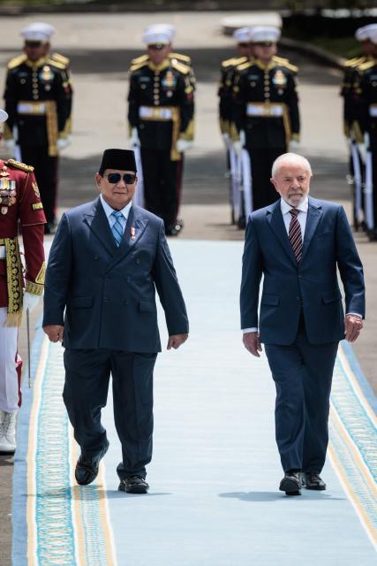 Brazil's President Luiz Inacio Lula da Silva (R) and Indonesia's President Prabowo Subianto inspect an honour guard before their bilateral meeting at the presidential palace in Jakarta on October 23, 2025. (Photo by Yasuyoshi CHIBA / AFP)