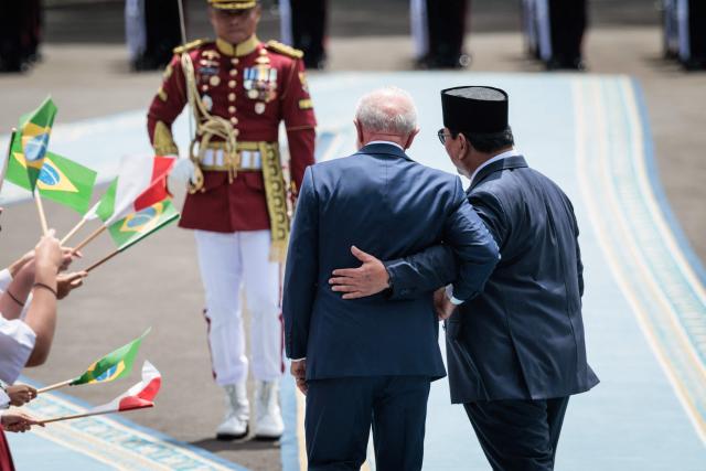 Brazil's President Luiz Inacio Lula da Silva (L) and Indonesia's President Prabowo Subianto react as they inspect an honour guard before their bilateral meeting at the presidential palace in Jakarta on October 23, 2025. (Photo by Yasuyoshi CHIBA / AFP)