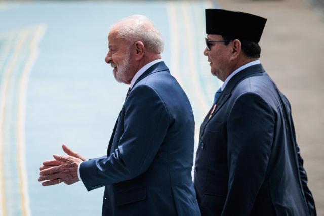 Brazil's President Luiz Inacio Lula da Silva (L) and Indonesia's President Prabowo Subianto react as they inspect an honour guard before their bilateral meeting at the presidential palace in Jakarta on October 23, 2025. (Photo by Yasuyoshi CHIBA / AFP)