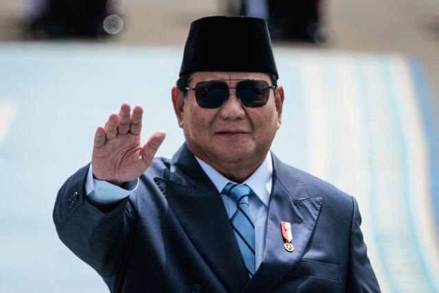 Indonesia's President Prabowo Subianto reacts to media as he walks with Brazil's President Luiz Inacio Lula da Silva to inspect an honour guard before their bilateral meeting at the presidential palace in Jakarta on October 23, 2025. (Photo by Yasuyoshi CHIBA / AFP)