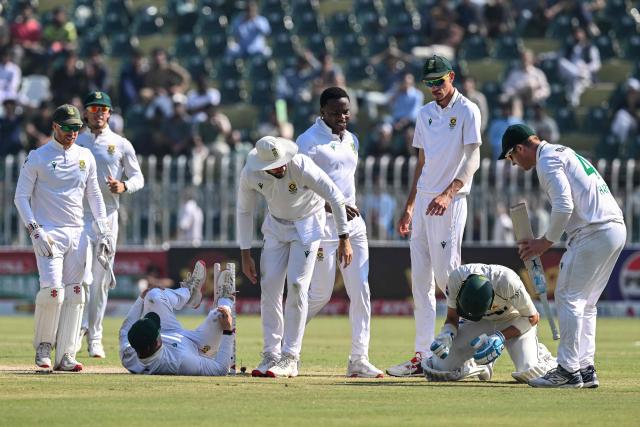 South Africa's players help Pakistan's Shaheen Shah Afridi (2R) after he collides with their teammate Ryan Rickelton (3L) during the fourth day of the second Test cricket match between Pakistan and South Africa at the Rawalpindi Cricket Stadium in Rawalpindi on October 23, 2025. (Photo by Aamir QURESHI / AFP)