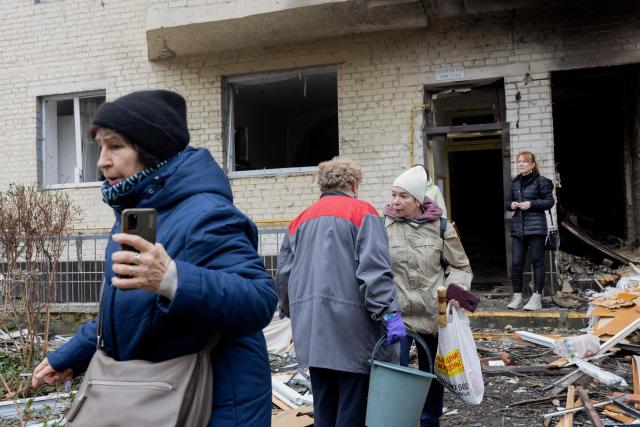 Residents stand near a damaged residential building following a drone attack in Kyiv, on October 23, 2025, amid the Russian invasion of Ukraine. (Photo by Tetiana DZHAFAROVA / AFP)