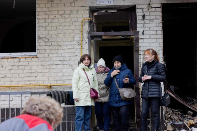 Residents stand near a damaged residential building following a drone attack in Kyiv, on October 23, 2025, amid the Russian invasion of Ukraine. (Photo by Tetiana DZHAFAROVA / AFP)