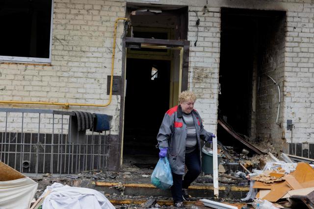 A local resident carries away debris near a damaged residential building following a drone attack in Kyiv, on October 23, 2025, amid the Russian invasion of Ukraine. (Photo by Tetiana DZHAFAROVA / AFP)