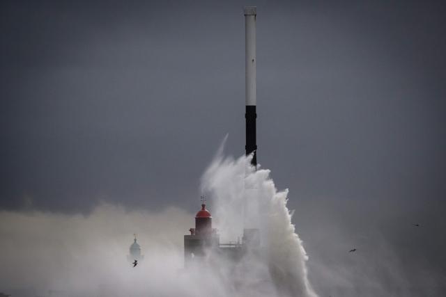 This photograph shows a waves breaking on the Digue Nord lighthouse in Le Havre, northwestern France, on October 23, 2025. France's Minister of the Economy, Finance, and Industrial, Energy and Digital Sovereignty, stated that "60,000 customers" were still without electricity by late afternoon on October 23, 2025, as Storm Benjamin, with wind gusts exceeding 100 km/h in much of the country, continues to move across France. (Photo by Loic VENANCE / AFP)