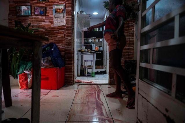 (FILES) A woman shows the scene where an alleged drug trafficker was reportedly killed by civil police while trying to escape and ran into the room of her nine-year-old daughter who witnessed the shooting, in the Jacarezinho favela, Rio de Janeiro, Brazil on May 6, 2021. The governor of the state of Rio de Janeiro, Claudio Castro, vetoed on October 23, 2025 a controversial measure that established the payment of bonuses to civil police officers for killing criminals, a proposal that sparked outrage in Brazil. (Photo by MAURO PIMENTEL / AFP)