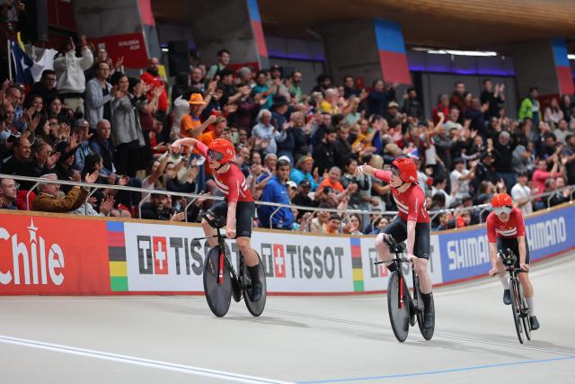 Denmark's  #13 Tobias Hansen (L) and #14 Niklas Larsen (R) celebrate after winning the gold medal in the men's team pursuit final event of the 2025 UCI Track World Championships at the Penalolen Velodrome, in Santiago, on October 23, 2025. (Photo by Javier TORRES / AFP)