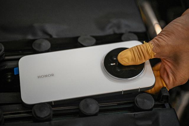 This photo taken on October 22, 2025 shows an employee working on an Honor Magic 8 smartphone production line at a factory of Chinese smartphone company Honor in Shenzhen, in southern China's Guangdong province. (Photo by Jade GAO / AFP)