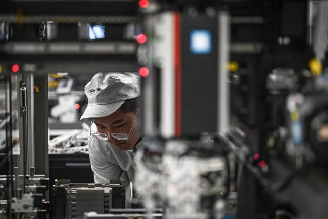 This photo taken on October 22, 2025 shows an employee working on a smartphone production line at a factory of Chinese smartphone company Honor in Shenzhen, in southern China's Guangdong province. (Photo by Jade GAO / AFP)
