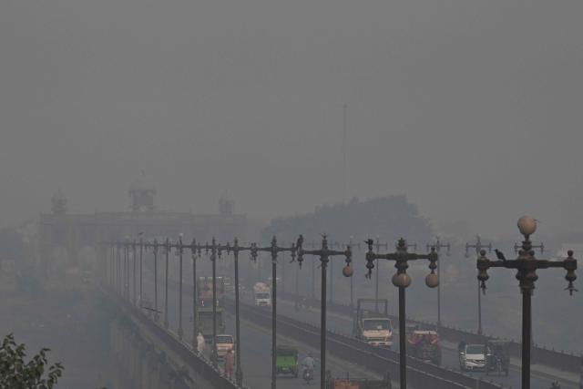 Commuters make their way along a road amid smoggy conditions in Lahore on October 24, 2025. (Photo by Arif ALI / AFP)