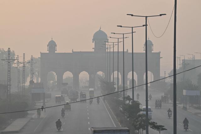 Commuters make their way along a road amid smoggy conditions in Lahore on October 24, 2025. (Photo by Arif ALI / AFP)