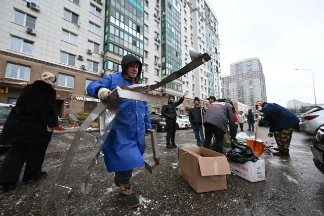 Workers clear debris in the yard of a damaged apartment building following a drone attack in Krasnogorsk in the Moscow region on October 24, 2025. An overnight Ukrainian drone attack injured a young boy and four others in a Moscow suburb, Russian officials said Friday. (Photo by Olesya KURPYAYEVA / AFP)