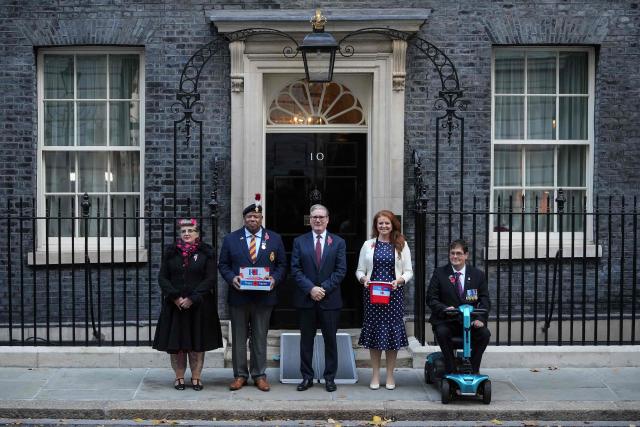 Britain's Prime Minister Keir Starmer attaches poses during a photo call with British veterans, after making a donation to the Royal British Legion's Poppy Appeal, outside 10 Downing Street in central London on October 24, 2025. In the run up to Remembrance Sunday, a commemoration of the contribution of British and Commonwealth servicepeople in the two World Wars and later conflicts, The Royal British Legion distributes remembrance poppies in return for donations to their "Poppy Appeal", which supports all current and former British military personnel. (Photo by Niklas HALLE'N / AFP)