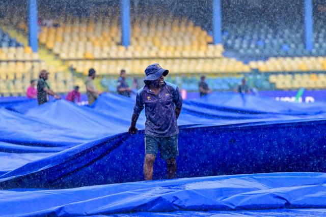 A ground staff covers the pitch as rain delays the start of the ICC Women's Cricket World Cup 2025 one-day international (ODI) match between Sri Lanka and Pakistan at the R. Premadasa International Cricket Stadium in Colombo on October 24, 2025. (Photo by Ishara S. KODIKARA / AFP)