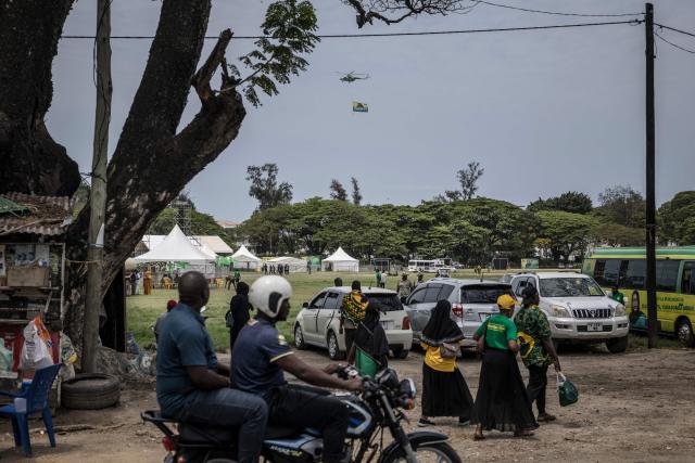 An helicopter flies the flag of the ruling Tanzanian Chama Cha Mapinduzi (CCM - Revolutionary Party) of the incumbent President Samia Suluhu Hassan as supporters reach the venue of the President’s campaign rally n Stone Town, on October 24, 2025. (Photo by MARCO LONGARI / AFP)