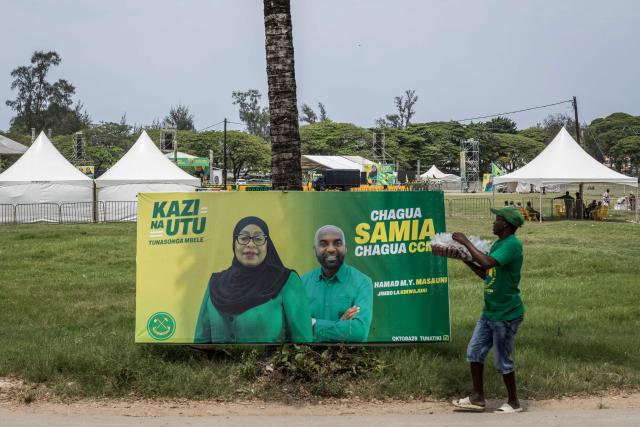 A street vendor walks past an electoral poster of the ruling Tanzanian Chama Cha Mapinduzi (CCM - Revolutionary Party) of the incumbent President Samia Suluhu Hassan in Stone Town, on October 24, 2025. (Photo by MARCO LONGARI / AFP)