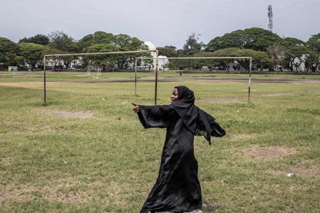 A young woman gestures as she walks in the grounds where a campaign rally of the ruling Tanzanian Chama Cha Mapinduzi (CCM - Revolutionary Party) of the incumbent President Samia Suluhu Hassan is scheduled to happen in Stone Town, on October 24, 2025. (Photo by MARCO LONGARI / AFP)