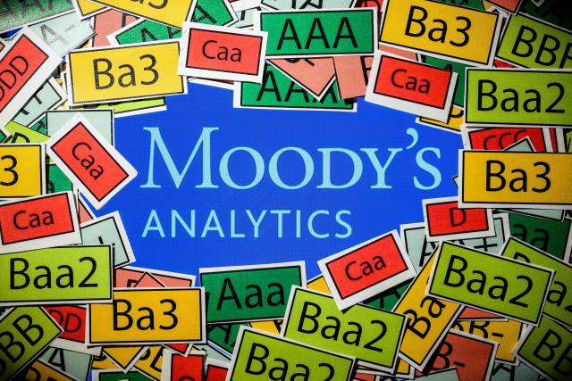 (FILES) This illustration photograph shows a screen displaying the logo of the rating agency Moody's Analytics and signs of the ratings used by rating agencies, in Toulouse on March 18, 2025. Moody's rating agency maintains France's rating but lowers its outlook on October 24, 2025. (Photo by Lionel BONAVENTURE / AFP)