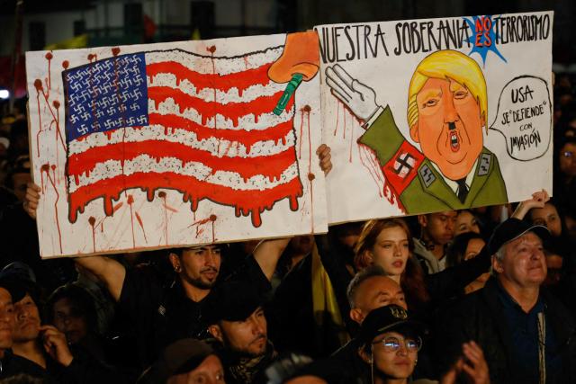 Demonstrators hold banners depicting the US flag and US President Donald Trump during a rally in support of Colombia's president Gustavo Petro at Bolivar Square in Bogota on October 24, 2025. US on Friday announced sanctions on Colombia's President Gustavo Petro, who Washington has accused of failing to curb illicit drug trafficking, alongside his wife and eldest son. (Photo by John Vizcaino / AFP)