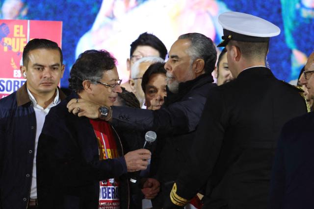 Colombia's President Gustavo Petro (2nd L) is embraced by Minister of the Interior Armando Benedetti during a rally at Bolivar Square in Bogota on October 24, 2025. US on Friday announced sanctions on Colombia's President Gustavo Petro, who Washington has accused of failing to curb illicit drug trafficking, alongside his wife and eldest son. (Photo by JOHN VIZCAINO / AFP)