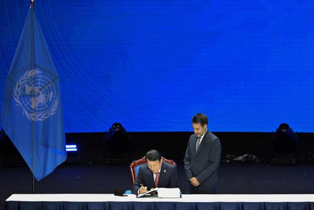 Vietnam's Minister of Public Security Luong Tam Quang inks his signature during the Signing Ceremony & High-Level Conference of the United Nations Convention Against Cybercrime at the National Convention Centre in Hanoi on October 25, 2025. (Photo by NHAC NGUYEN / AFP)