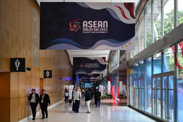 Members of the media walk under the Association of Southeast Asian Nations (ASEAN) banners ahead of the 47th ASEAN Summit in Kuala Lumpur on October 25, 2025. US President Donald Trump arrives in Malaysia on October 26 for the Association of Southeast Asian Nations (ASEAN) summit -- a meeting he skipped several times in his first term. (Photo by Mohd RASFAN / AFP)