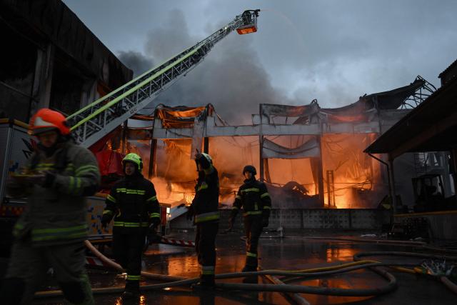 Ukrainian firefighters extinguish a fire at the site of a food warehouse following a Russian missile strike in Kyiv early on October 25, 2025, amid the Russian invasion of Ukraine. (Photo by Genya SAVILOV / AFP)