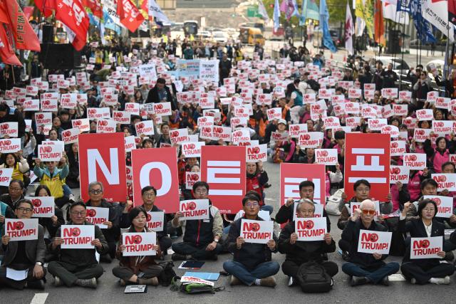 Protesters hold up signs reading "No Trump!" during a rally, condemning US President Donald Trump's pressure for increased South Korean investment in the US, in Seoul on October 25, 2025. Trump headed for Asia on October 25 and high-stakes trade talks with Chinese counterpart Xi Jinping, saying that he would also like to meet North Korean leader Kim Jong Un on his trip. (Photo by Jung Yeon-je / AFP)