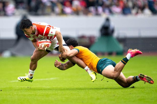 Japan's Lee Seungsin is tackled by Australia's Hunter Paisami during the international rugby union Test match between Japan and Australia at the National Stadium in Tokyo on October 25, 2025. (Photo by Philip FONG / AFP)