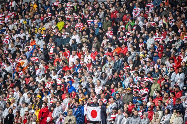 Spectators in rain gear watch the international rugby union Test match between Japan and Australia at the National Stadium in Tokyo on October 25, 2025. (Photo by Philip FONG / AFP)