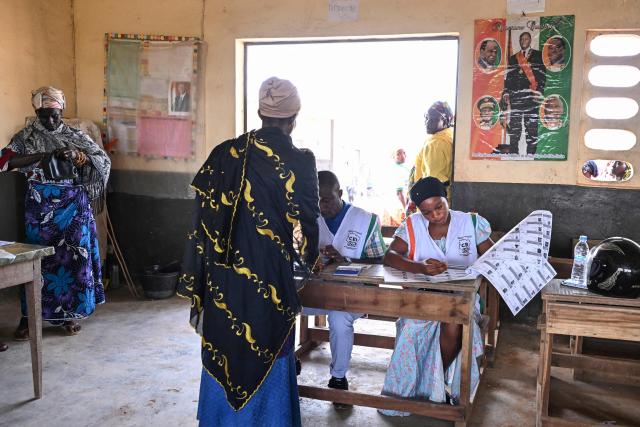 An Independent Electoral Commission of Ivory Coast (CEI) official captures the biometric data of a voter at a polling station in Agboville on October 25, 2025 during Ivory Coast's presidential elections. (Photo by Issouf SANOGO / AFP)