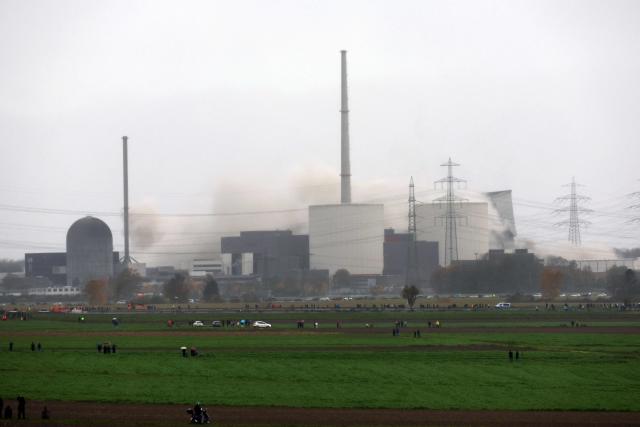 A photo taken on October 25, 2025 shows the controlled demolition of the second (R) of the cooling towers of the decommissioned nuclear power plant Gundremmingen in Gundremmingen, southern Germany. The 160-meter-high towers were built between 1977 and 1980 and have been a prominent landmark in the region for almost 50 years. The demolition of the cooling towers is part of the scheduled dismantling of the nuclear power plant as a result of the nuclear phase-out. It was one of the largest nuclear sites in Germany. (Photo by Karl-Josef Hildenbrand / AFP)
