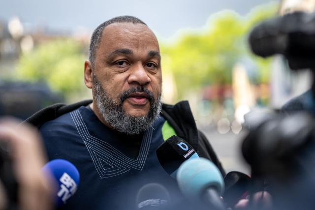 (FILES) French controversial humorist Dieudonne MBala MBala talks to the press as he arrives to testify on the second day of Tariq Ramadan's trial at the Geneva court house on May 16, 2023. The French gendarmerie on the evening of October 24, 202 on interrupted a banned show by controversial comedian Dieudonne, who has been convicted several times, in Vieillevigne, Loire-Atlantique department, the prefecture told AFP on October 25, 2025. (Photo by Fabrice COFFRINI / AFP)
