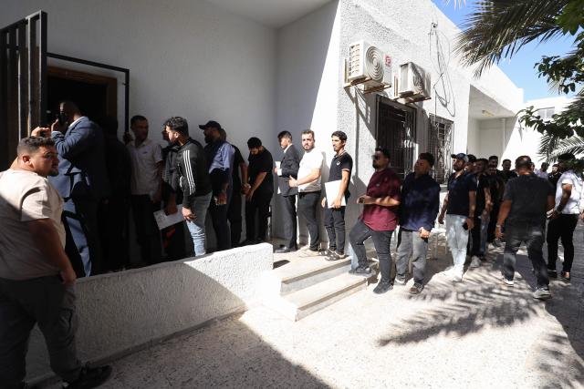 Syrian nationals wait at a service office affiliated with the Syrian Embassy in Tripoli after the Syrian Foreign Ministry announced that it will grant free return tickets to its citizens wishing to leave Libya, on October 25, 2025.  (Photo by Mahmud Turkia / AFP)
