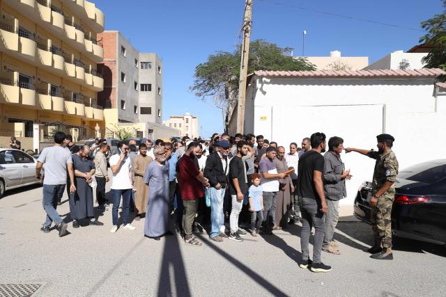 Syrian nationals wait outside service offices affiliated with the Syrian Embassy in Tripoli after the Syrian Foreign Ministry announced that it will grant free return tickets to its citizens wishing to leave Libya, on October 25, 2025.  (Photo by Mahmud Turkia / AFP)