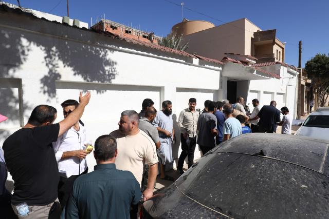 Syrian nationals wait outside service offices affiliated with the Syrian Embassy in Tripoli after the Syrian Foreign Ministry announced that it will grant free return tickets to its citizens wishing to leave Libya, on October 25, 2025.  (Photo by Mahmud Turkia / AFP)