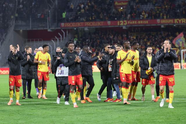 Lens' players acknowledge their supporters as they celebrate their victory at the end of the French L1 football match between RC Lens and Olympique de Marseille (OM) at the Stade Bollaert-Delelis in Lens, northern France, on October 25, 2025. (Photo by Francois LO PRESTI / AFP)